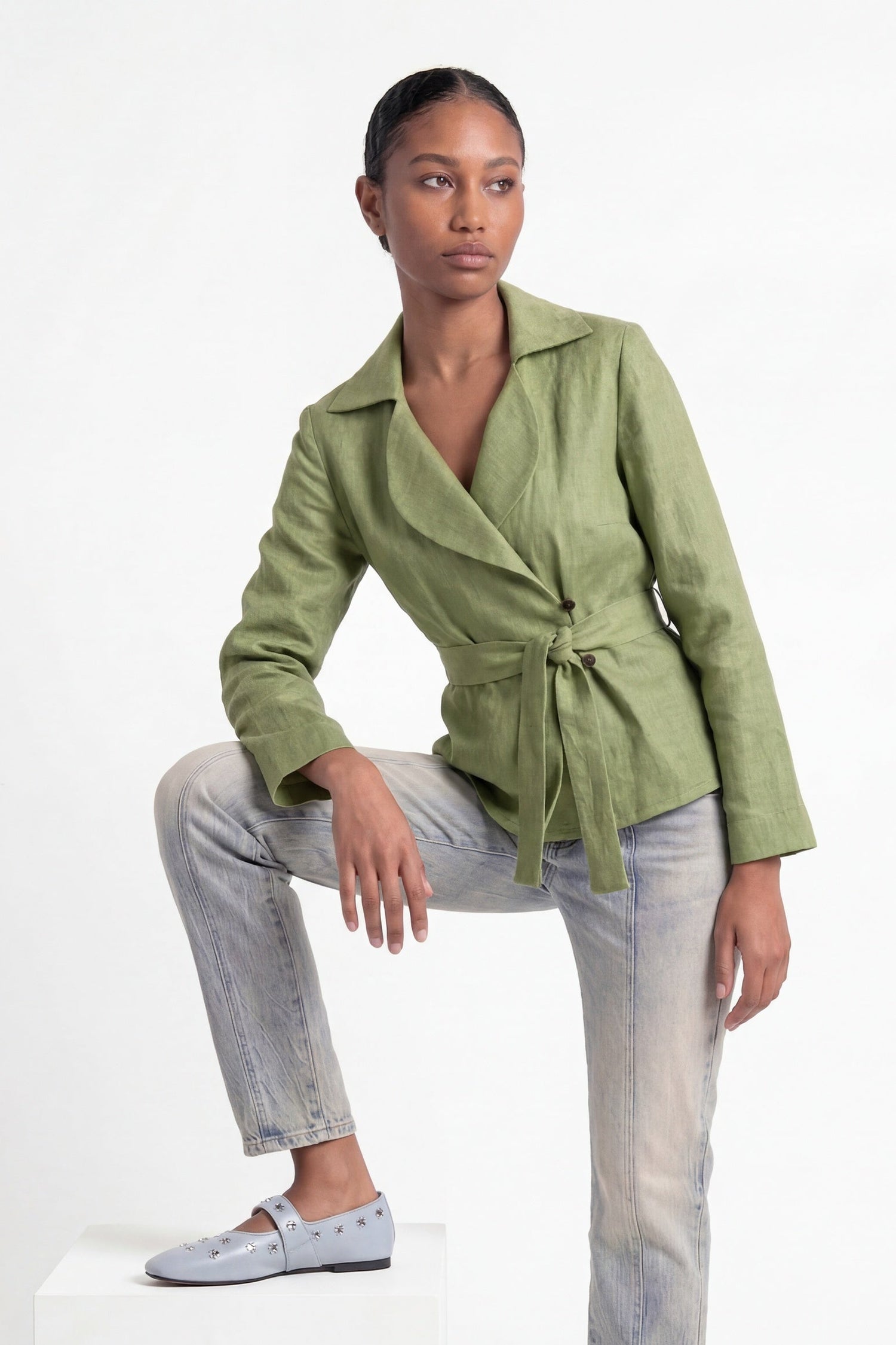 Woman wearing a green jacket and light gray pants on a white background